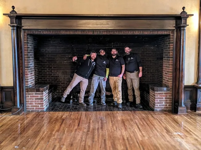 Evergreen Chimney Sweep Team Four men from Evergreen Chimney Sweep standing inside a huge fireplace at the Spokane Club historical building.